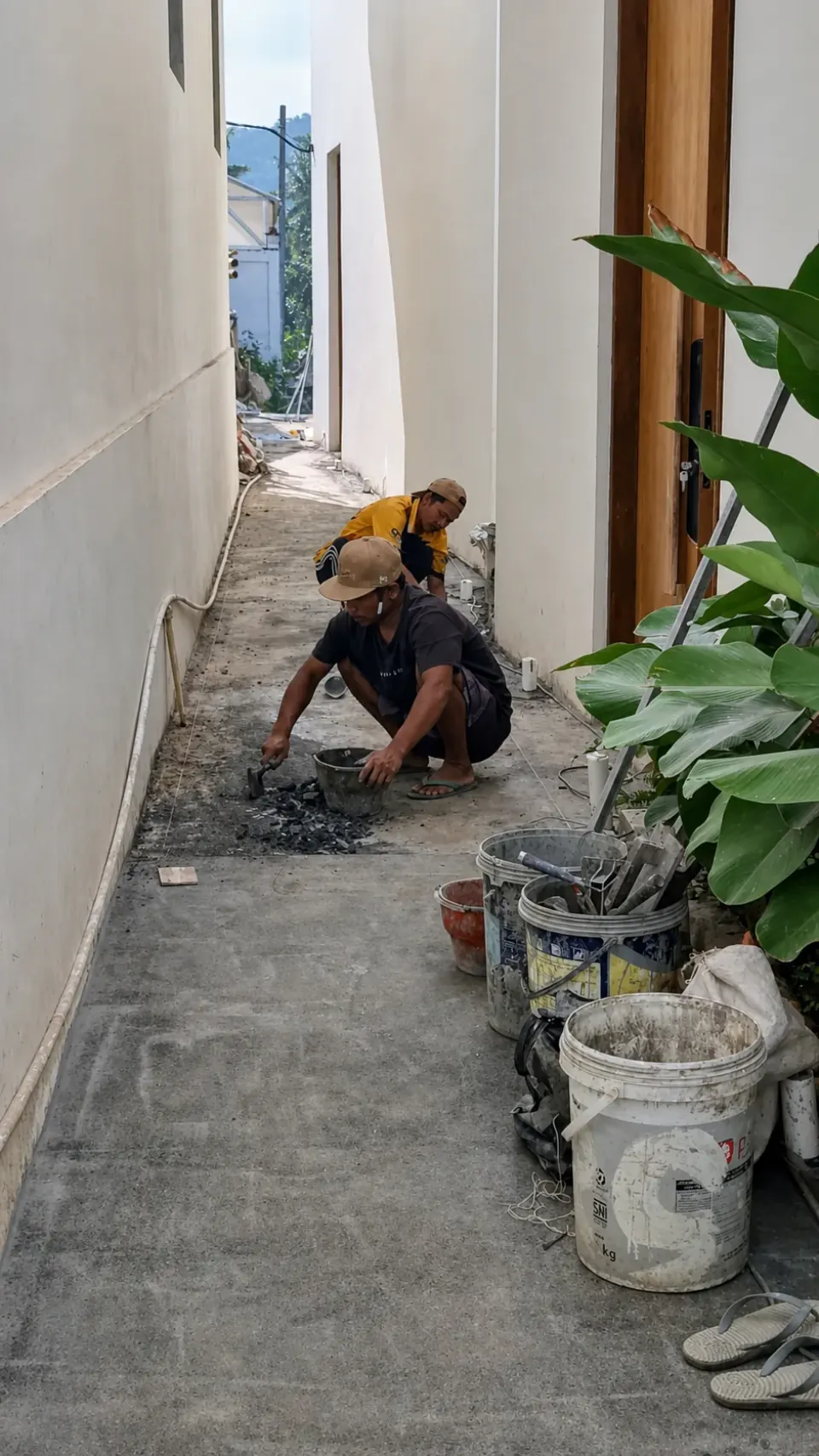 Dua pekerja melakukan perbaikan pada koridor sempit sebuah villa.